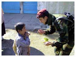 Un Carabiniere porge del cibo ad un bambino albanese.
