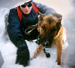 Carabiniere sciatore con cane addestrato per il recupero di dispersi sotto la neve.