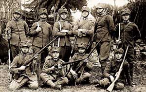 Allievi carabinieri e carabinieri allievi a piedi (questi distinguibili dagli alamari) in uniforme grigio-verde da esercitazione. I militari sono armati di fucile modello 91.